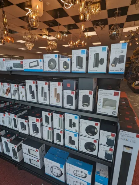 Shelves stocked with boxed outdoor wall lights, bulkheads and bollard lights from Zinc and Coast in the lighting showroom