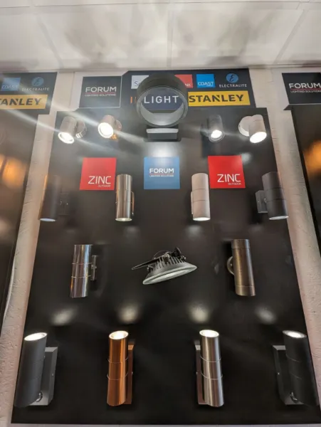 Display board of stainless steel, copper and black up-and-down cylinder wall lights and spotlights, with Zinc and Forum branding
